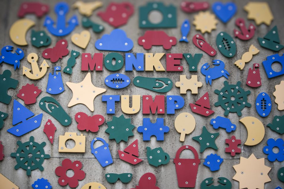 Brightly coloured cut-out shapes, anchors, boats, crabs and cameras, fixed to a concrete wall around the words Monkey Tump.