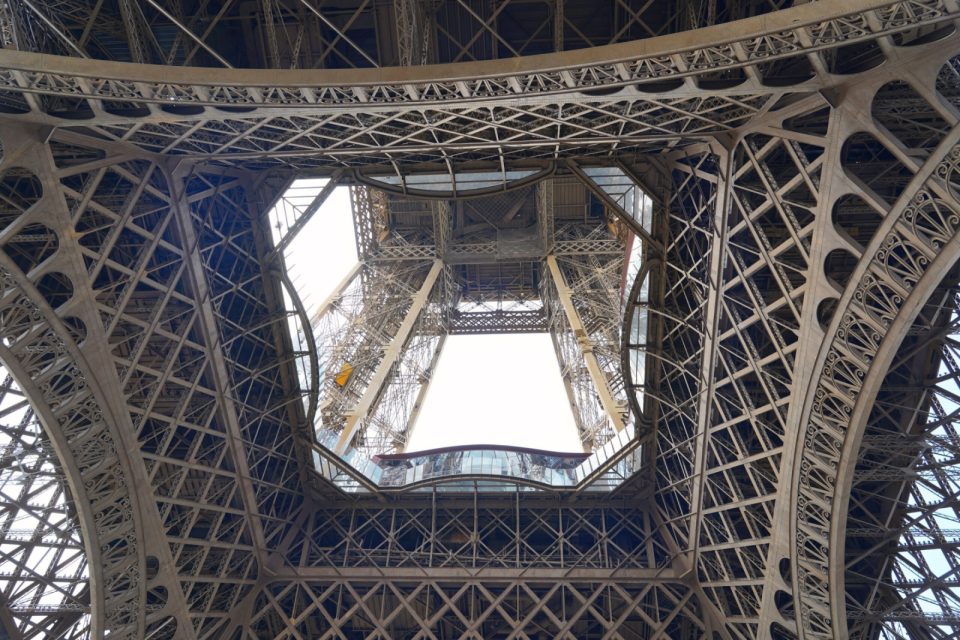 Looking straight up through the iron lattice of the Eiffel Tower.